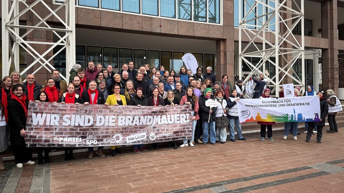 Eine Gruppe von Personen halten zwei Banner mit einer Botschaft. 
