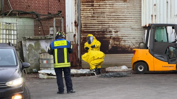 Feuerwehrleute in gelben Chemieanzügen auf einem Industriegelände