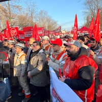 Streikende mit roten Fahnen und Plakaten. 