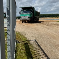 Bauzaun vor einem Bagger, der Kies am Niederrhein abbaut