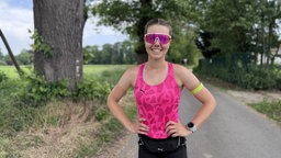  Marathon-Läuferin Joyce Hübner lächelt in die Kamera, Sie trägt ein rosanes Top und eine rosane Sportbrille.