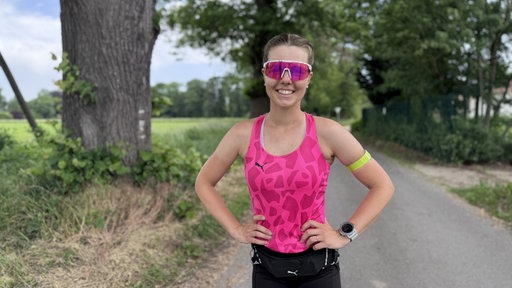  Marathon-Läuferin Joyce Hübner lächelt in die Kamera, Sie trägt ein rosanes Top und eine rosane Sportbrille.