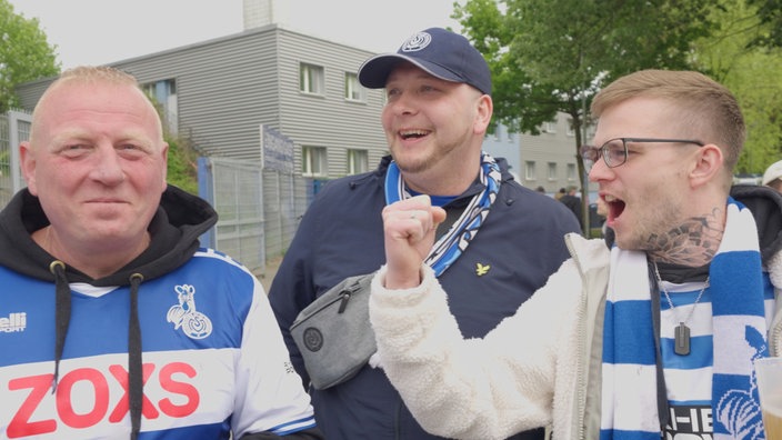 Drei Fans vom MSV Duisburg unterhalten sich nach dem Spiel vor dem Stadion.