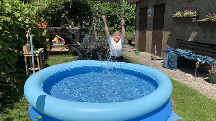Olga, eine Frau, wirft Wasser aus ihrem Pool in die Höhe.