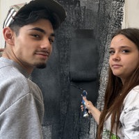 Zwei Schüler streichen eine Wand mit schwarzer Farbe