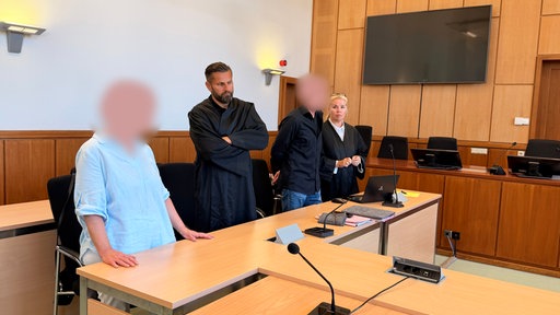 Die Angeklagten stehen neben Verteidiger und Verteidigerin im Gerichtssaal.