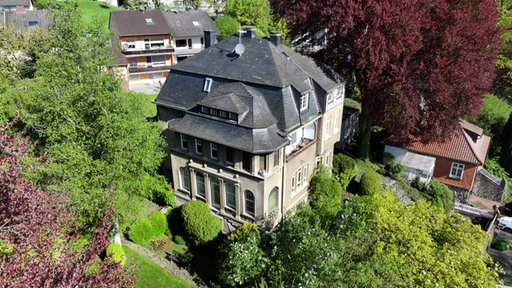 Luftaufnahme einer historischen Villa in Wetter-Wengern, die von Bäumen und Sträuchern umgeben ist