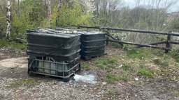 Zwei große mit Folie eingewickelte Behälter mit Flüssigkeit, auch einem tropft eine schäumende Flüssigkeit