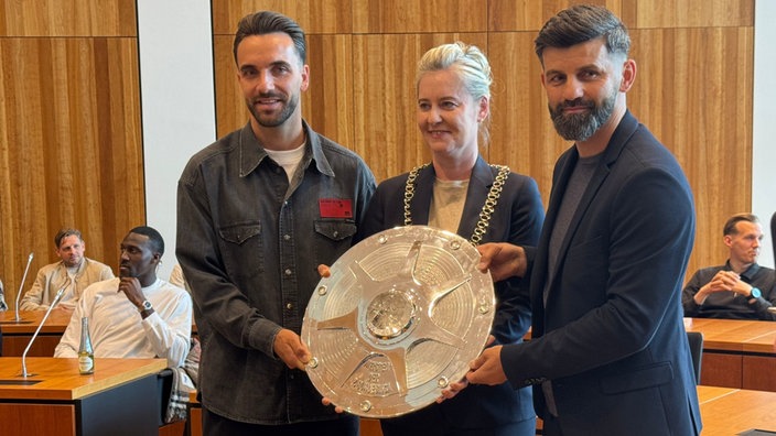 Trainer Miron Muslić posiert mit Kenan Karamen und der Oberbürgermeisterin für ein Foto