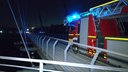 Ein Feuerwehrfahrzeug mit Blaulicht steht im Dunkeln auf der Brücke über den Rhein-Herne-Kanal in Gelsenkirchen