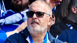 Ein Mann mit Sonnenbrille sitzt im Stadion