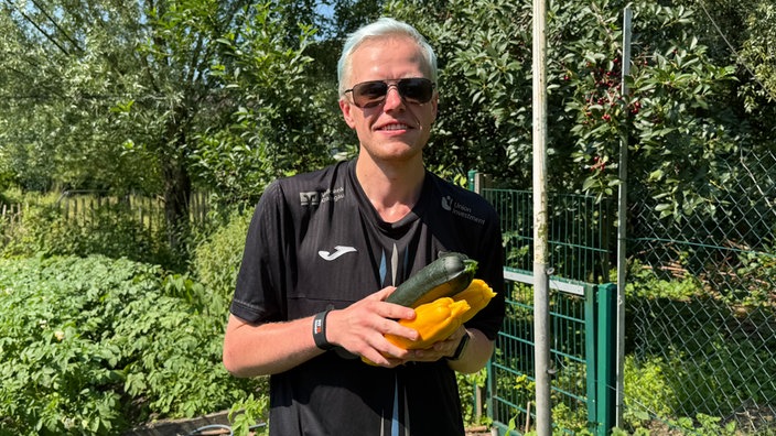 Mann mit Zucchinis in der Hand