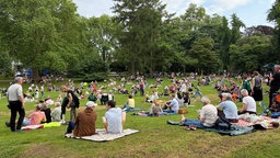 Mehrere Personen sitzen auf einer Wiese