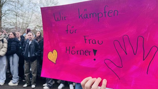 Auf dem Bild ist ein Demo-Schild mit der Aufschrift "Wir kämpfen für Frau Hörner" zu sehen.