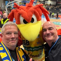 Selfie unseres Autors Christian Beisenherz mit dem Maskottchen Felix, einem roten Feuervogel, und WDR-Sportreporter Michael Bodenröder