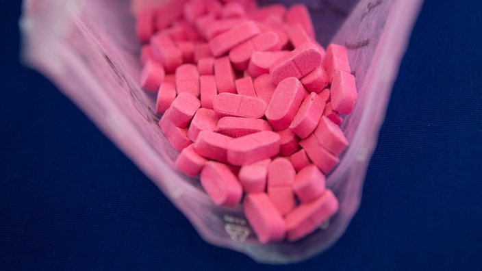 Das Symbolfoto zeigt pinke Ecstasy-Tabletten in einer offenen Plastiktüte.