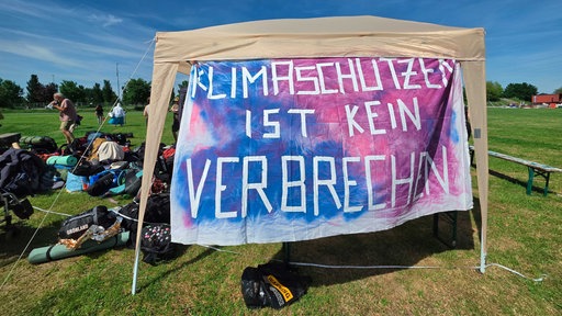 Ein Zelt, vor dem ein Plakat mit der Aufschrift "Klimaschutz ist kein Verbrechen" hängt.