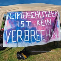 Ein Zelt, vor dem ein Plakat mit der Aufschrift "Klimaschutz ist kein Verbrechen" hängt.