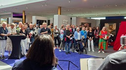 Eine Menschengruppe steht zusammen und singt.