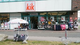 Außenansicht einer Kik-Filiale mit Kleidungsständern davor.