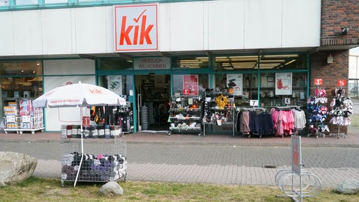 Außenansicht einer Kik-Filiale mit Kleidungsständern davor.