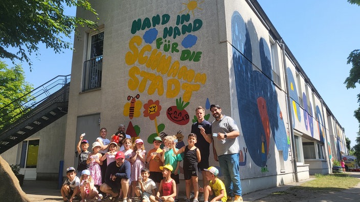 Kinder und Erwachsene vor einer Wand