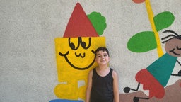 Ein Kind vor einer bemalten Wand