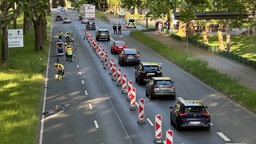 Eine Straße von einer Brücke aus gesehen, auf einer Spur reihen sich die Autos, die Polizei steht mit mehreren Personen daneben