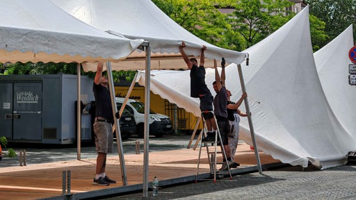 Vier Männer bauen ein Gastro-Zelt auf dem Altstadtmarkt auf.