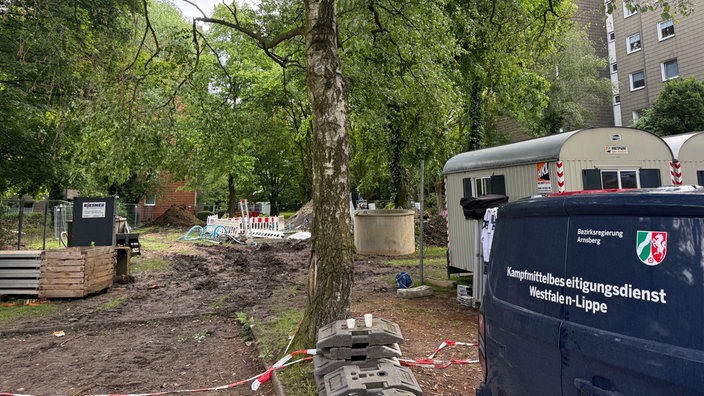 Zwischen mehreren Hochhäusern liegt die Fundstelle mehrerer Bomben. Im Vordegrund steht ein Auto des Kampfmittelbeseitigungsdienstes.