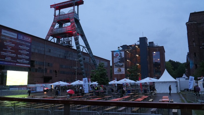 Das weitestgehend leere Arenagelände mit Leinwand vor dem Förderturm der Zeche