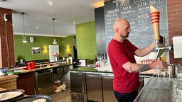 Ein Biersommelier steht an der Bar und zapft ein Bier ab.