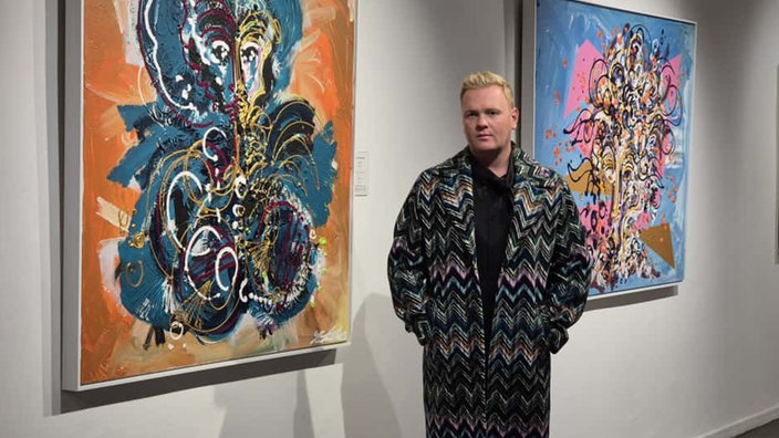 Der Künstler Leon Löwentraut steht zwischen seinen Kunstwerken. 