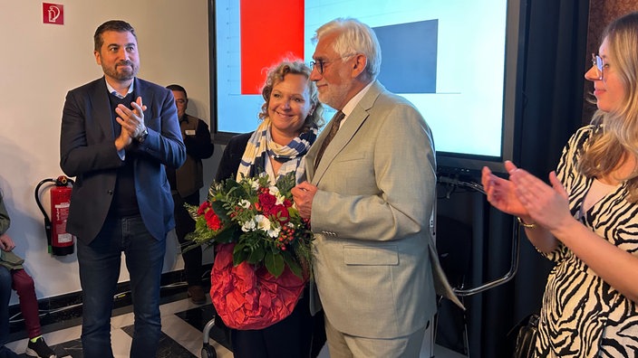 Der neue Oberbürgermeister von Bochum, Lukat, steht mit seiner Frau, die einen Strauß Blumen in der Hand hält, im Bochumer Rathaus