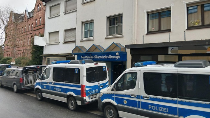 Einsatzfahrzeuge der Polizei stehen vor einem Wohnhaus.