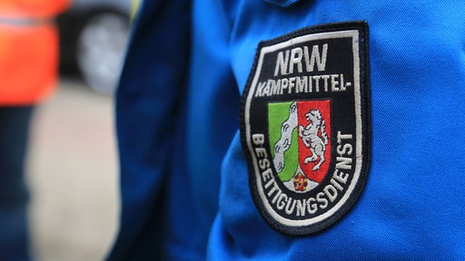 Ein Wappen mit der Aufschrift "NRW-Kampfmittel-Beseitigungsdienst" ist auf einer Jacke aufgenäht. 