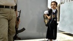 Ein irakisches Mädchen verlässt eine Grundschule in Bagdad, sie blickt zu einem Soldaten mit Waffe neben ihr