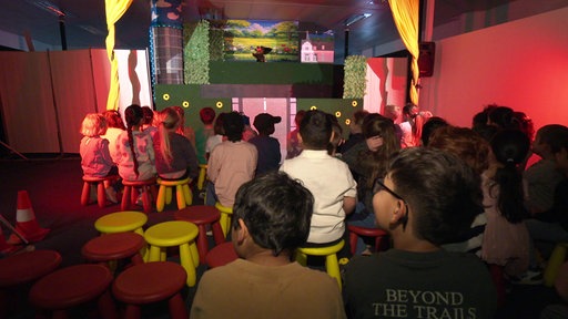 Eine Gruppe Kindergarten-Kinder schaut sich ein Puppentheater an.