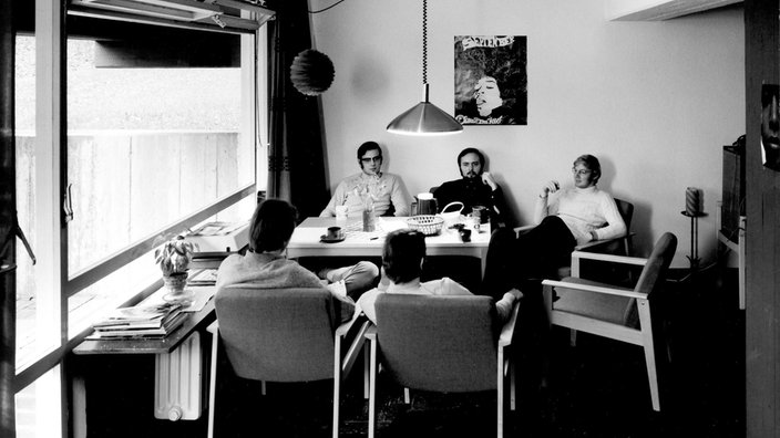 Auf dem alten schwarz-weiß-Foto sind fünf Männer, die an einem Tisch sitzen.