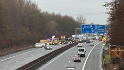 Nach dem Brand eines Reisebusses stehen Einsatzfahrzeuge und der ausgebrannte Bus auf der A52 in Richtung Essen, in Richtung Düsseldorf fahren Autos
