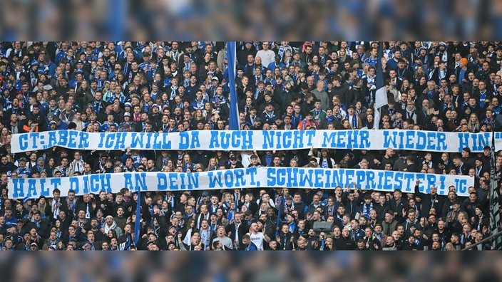 Fans vom Schalker Fuballverein halten Banner in der Hand mit der Aufschrift "CT: "ABER ICH WILL DA AUCH NICHT MEHR WIEDER HIN" HALT DICH AN DEIN WORT, SCHWEINEPRIESTER! JC"