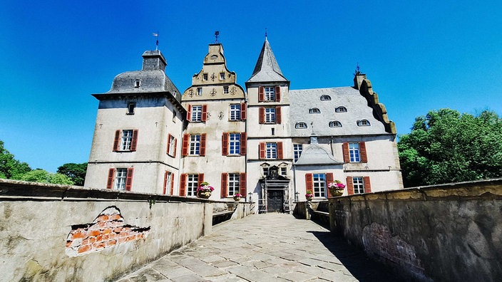Eine Brücke aus Stein führt zu einem Renaissance-Schloss mit Türmen und Zinnen