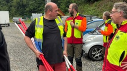 Mehrere Personen in Warnkleidung und Rot-Weiß gestreifen Pfosten