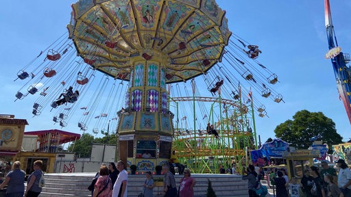 Ein Kettenkarussell auf einer Kirmes in Oberhausen dreht sich mit ersten Fahrgästen in der Luft.