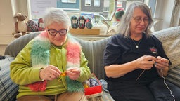 Annette Bremicker-Kaslack und Chefin Simone Tamse beim stricken auf der Couch.