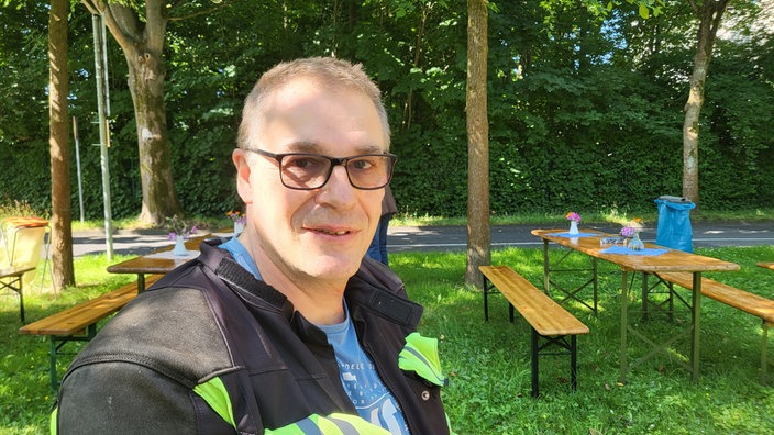 Mann mit Brille auf Bank und Motorradkluft