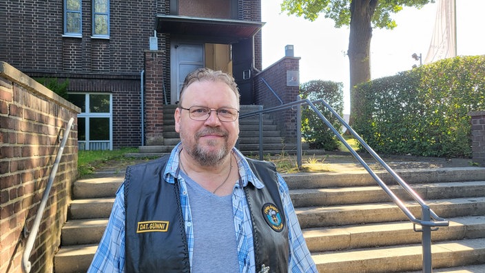 Mann in Lederkutte vor Kirche