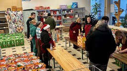 Ehrenamtliche verteilen Taschen mit Lebensmitteln