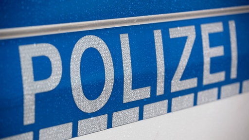 Auf einem Polizeiauto steht in silberner Schrift auf blauem Grund das Wort "Polizei"