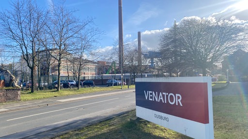 Schild mit der Aufschrift Venator mit dem Produktionsgelände der Firma im Hintergrund